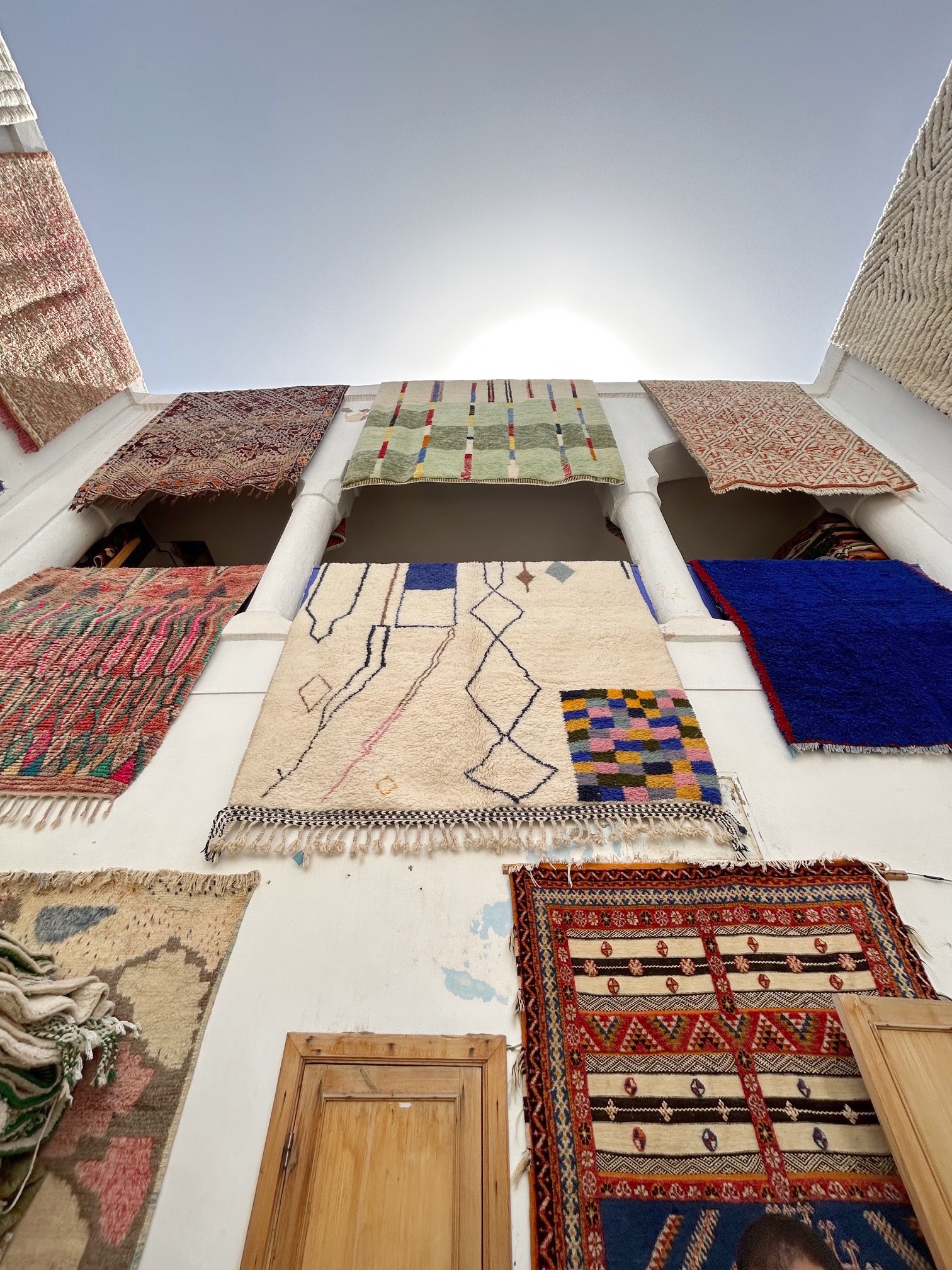 Cosa guide Marrakech Marokkanske berbertepper fra Cosa hengende på en vegg under en blå himmel. Tepper i alle farger, fra naturhvite bakgrunner til blå, rødlige toner og grønn.