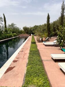 Cosa tur til Marrakech. Bildet viser et langt basseng i rosa og grønne omgivelser