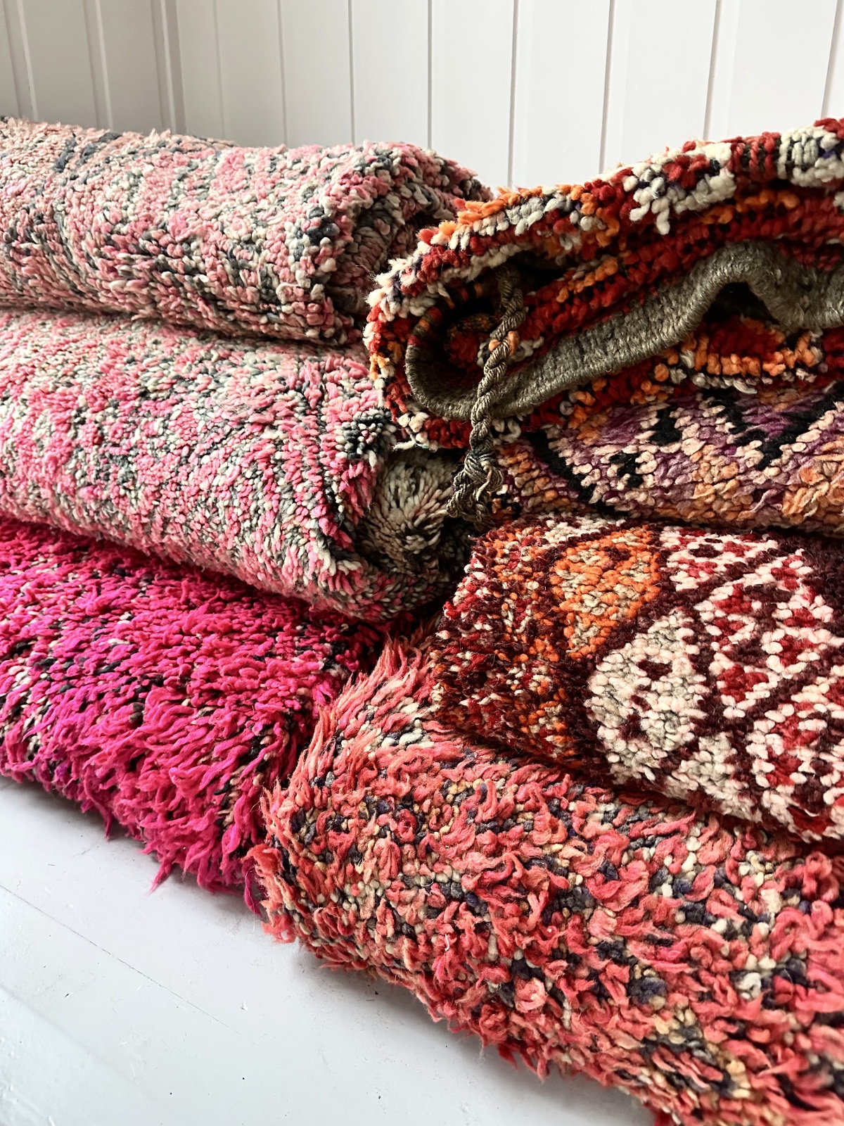 Marokkanske berbertepper i bunker i et lyst og tiltalende lokale. Vintagetepper i vakre farger, sm rosa, burgunder, oransje.