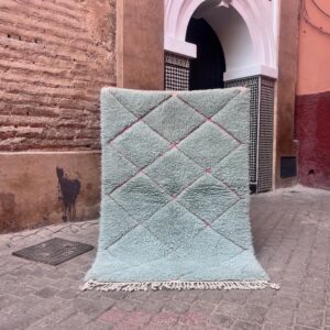 Et lyseblått Beni Ourain teppe med rosa diamantmønster og hvite frynser. Mål 157x108 cm, pris 5500,-
