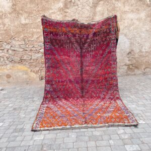 Et håndknyttet marokkansk vintageteppe fra Beni Mguild regionen i Marokko. Tykt og mykt, 100% naturlig ull. Lang lugg. Vist frem foran gamle bymurer i Marrakech