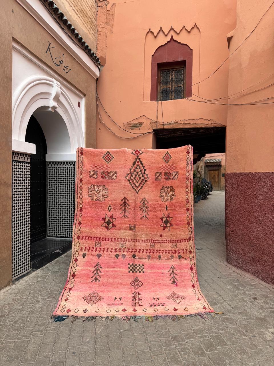 Vintage rosa marokkansk beojaad teppe. Diamant og stjerne mønstre som kjennetegner stammen. Teppet henger i en gate i Marrakech.